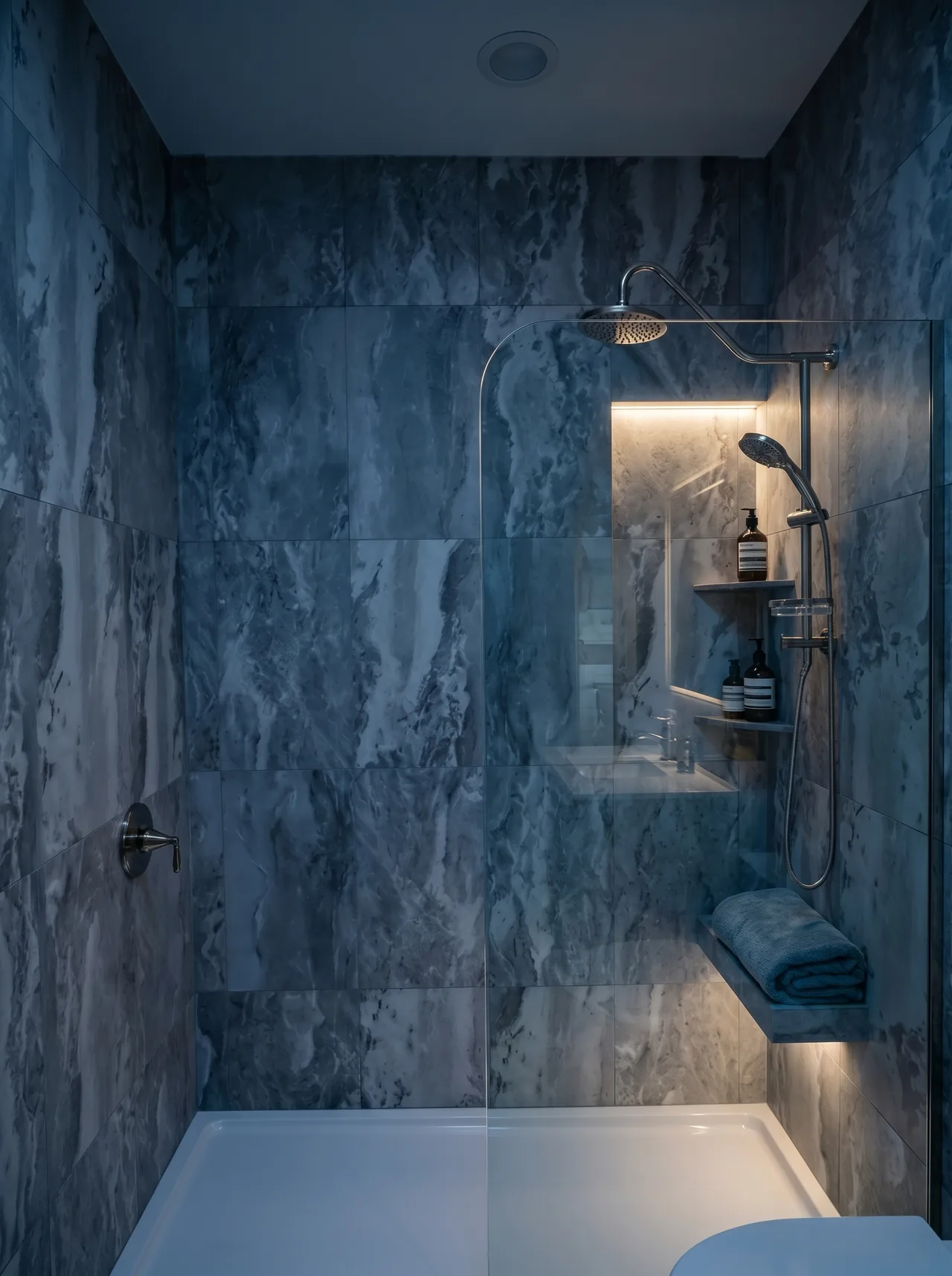 Completed shower clad in grey veined stone-look tile with a glass screen, rain head, and handheld on a sliding bar